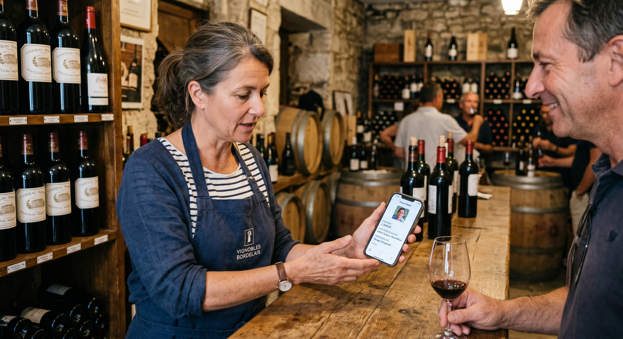 Vigneron consultant la fiche client d'un visiteur dans le CRM vin sur son smartphone au caveau